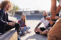 Amigos conversando e saindo no ensolarado parque de skate — Fotografia de Stock