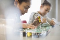 Étudiante concentrée assemblant le circuit imprimé en salle de classe — Photo de stock