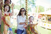 Family on carousel in amusement park — Stock Photo