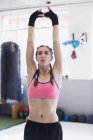 Jovem mulher esticando-se com os braços sobrecarga no ginásio — Fotografia de Stock