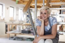 Ritratto artista sorridente su gradini in studio — Foto stock