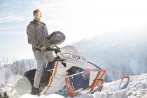 Mann fährt Schneemobil in sonnigem, verschneitem Feld — Stockfoto