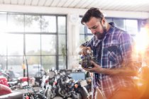 Motorcycle mechanic greasing engine part in workshop — Stock Photo