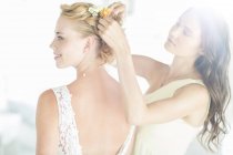 Bridesmaid helping bride with hairstyle in garden — Stock Photo