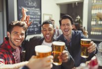 Retrato homens entusiastas amigos brindar copos de cerveja no bar — Fotografia de Stock
