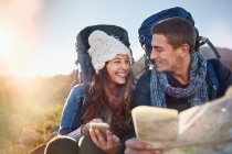 Young couple with backpacks hiking checking map — Stock Photo