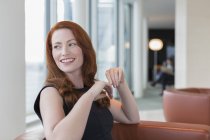 Smiling businesswoman with red hair looking over shoulder in lounge — Stock Photo