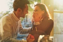 Парень делает предложение удивленной, счастливой девушке в кафе — стоковое фото
