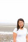 Портрет улыбающейся китаянки на пасмурном пляже — стоковое фото