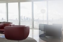 Sedie in pelle e divano nel moderno salotto ufficio urbano con vista sulla città — Foto stock
