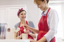 Smiling female caterers baking, making cupcake pops in kitchen — Stock Photo