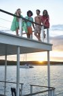 Young friends hanging out and drinking on summer houseboat at sunset — Stock Photo