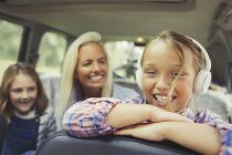 Retrato sorridente menina usando fones de ouvido no banco de trás do carro — Fotografia de Stock