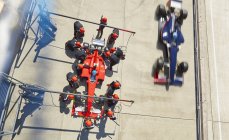 Tripulación aérea reemplazando neumáticos en Fórmula 1 coche de carreras en pit lane - foto de stock