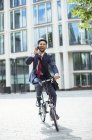 Businessman talking on cell phone on bicycle — Stock Photo