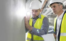 Мужчина-инженер с фонариком, осматривающий подземную стену на строительной площадке — стоковое фото