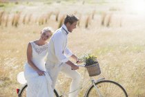 Happy young couple riding bike in meadow — Stock Photo