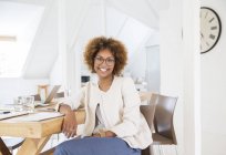 Портрет жінки, сидячи за столом в офісі і посміхаючись — стокове фото