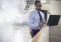 Homme d'affaires utilisant un ordinateur portable au mur de la cabine de bureau — Photo de stock