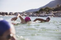 Aktive Schwimmerinnen am Tag auf See gegen Ufer — Stockfoto