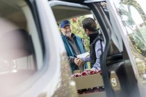 Male farmer and customer handshaking at truck in apple orchard — Stock Photo