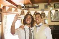 Bridegroom and best man photographing self in domestic room — Stock Photo