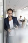 Retrato sonriente empresario sosteniendo tableta digital en la oficina - foto de stock