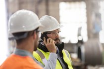 Сталеві робітники розмовляють по мобільному телефону на заводі — стокове фото