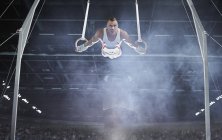 Ginasta masculina se apresentando em anéis de ginástica na arena — Fotografia de Stock
