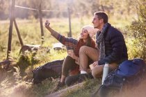 Молодая пара отдыхает от походов, делает селфи с камерой телефона — стоковое фото