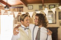 Bridegroom and best man embracing in domestic room — Stock Photo