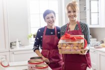 Retrato sonriente catering femenino mostrando caja envuelta de pasteles en la cocina - foto de stock