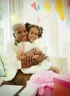 Портрет улыбающейся бабушки и внучки, обнимающихся на дне рождения — стоковое фото