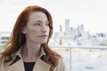 Portrait femme d'affaires coûteuse aux cheveux roux regardant loin sur le balcon urbain — Photo de stock