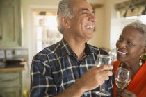 Riendo pareja mayor bebiendo vino blanco - foto de stock
