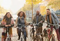 Retrato sorridente amigos bicicleta equitação no urbano outono rua, Amsterdã — Fotografia de Stock