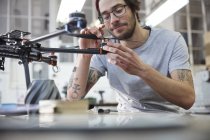 Designer masculin avec tatouages assemblage drone dans l'atelier — Photo de stock