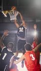 Молодой баскетболист бросает мяч в кольцо с защитниками внизу — стоковое фото