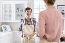 Smiling hembra catering atando delantales en la cocina - foto de stock