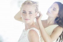 Brautjungfer hilft Braut mit Frisur im häuslichen Zimmer — Stockfoto