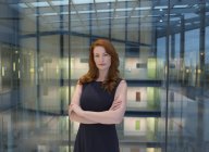 Portrait femme d'affaires confiante aux cheveux roux dans l'atrium de bureau moderne — Photo de stock