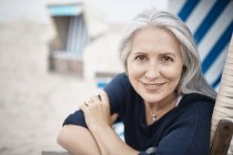Retrato sonriente mujer mayor en la playa - foto de stock