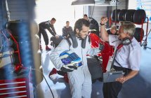 Driver and formula one race car driver cheering, celebrating victory in repair garage — Stock Photo