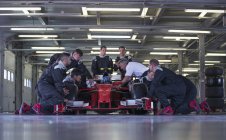 Команда гоночного автомобіля працює на гоночному автомобілі в гаражі — стокове фото