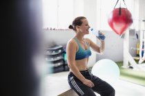 Boxer feminino bebendo água e descanso pós treino no ginásio — Fotografia de Stock