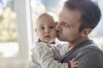 Portrait baby daughter being kisses on cheek by father — Stock Photo