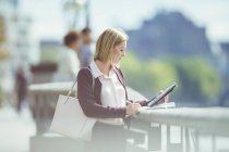 Businesswoman using digital tablet at urban waterfront — Stock Photo