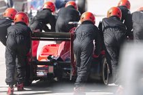 Pit crew pushing formula one race car out of pit lane — Stock Photo