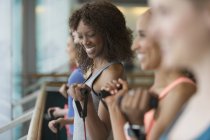 Mujeres sonrientes usando bandas de resistencia en el gimnasio de clase de ejercicio - foto de stock