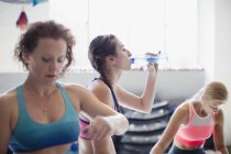 Молоді жінки п'ють воду і відпочивають після тренування в спортзалі — стокове фото